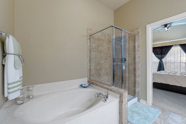 Ensuite bathroom featuring ceiling fan, connected bathroom, a garden tub, and a shower stall | Image 17