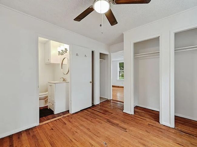 Unfurnished bedroom featuring multiple closets, light wood-style flooring, ensuite bath, a ceiling fan, and a textured ceiling | Image 10