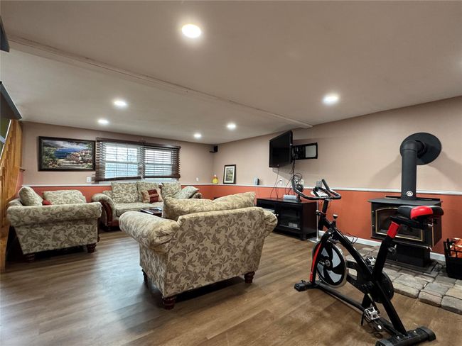 Living room with wood finished floors, a wood stove, and recessed lighting | Image 22