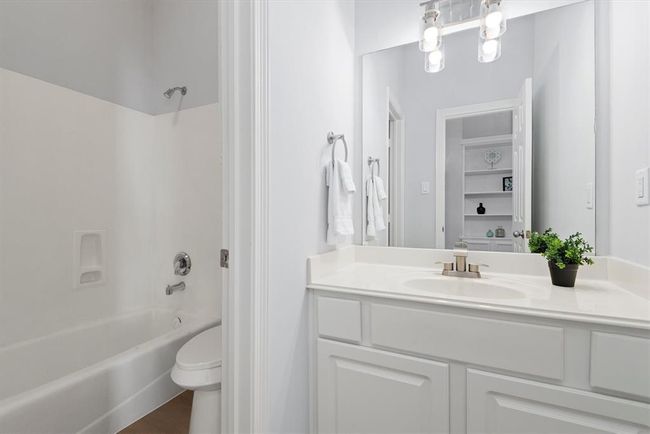 This spacious bathroom features a separate water closet-style layout, with a door dividing the toilet and tub area from the main vanity space—perfect for added privacy and functionality. The layout allows for comfortable, shared use. | Image 16