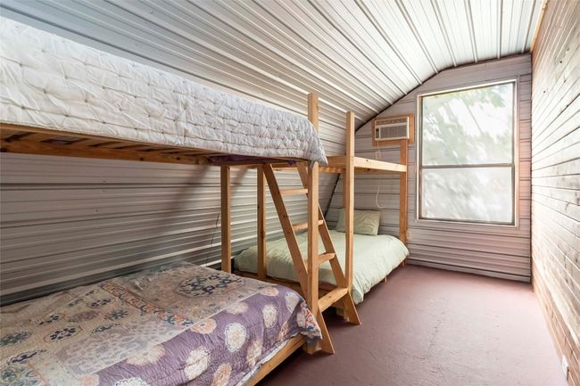 Bunkhouse dedroom with lofted ceiling, a wall mounted AC, and wood walls | Image 27
