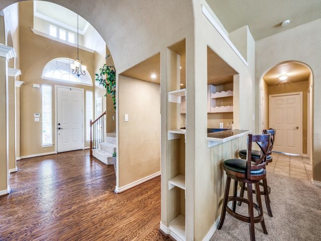 Foyer entrance with arched walkways, a high ceiling, wood finished floors, stairway, and bar | Image 8