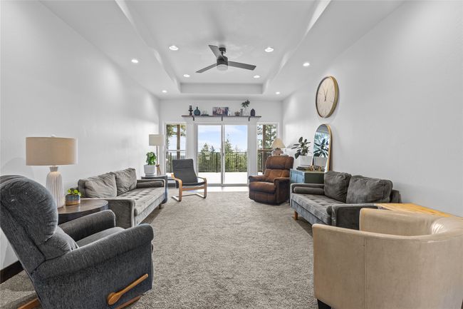 Carpeted living area with recessed lighting, ceiling fan, a high ceiling, and a tray ceiling | Image 13