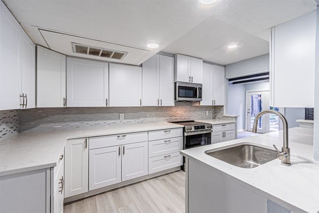 Kitchen with white cabinetry, appliances with stainless steel finishes, sink, and backsplash | Image 4