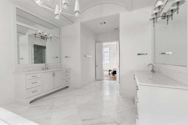 Dual vanity areas feature marble countertops, statement lighting, and furniture style built in cabinetry. | Image 26