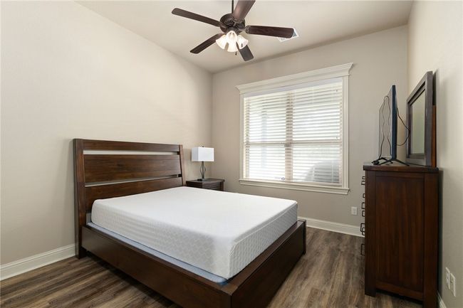 This home includes two secondary bedrooms, each featuring wood-finished floors, a ceiling fan, and a large window that fills the space with natural light, creating a bright and welcoming atmosphere. | Image 23