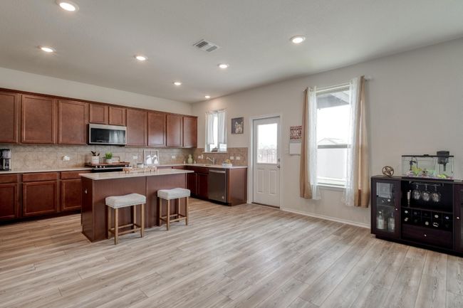 Kitchen with light countertops, a breakfast bar, appliances with stainless steel finishes, visible vents, and decorative backsplash | Image 13