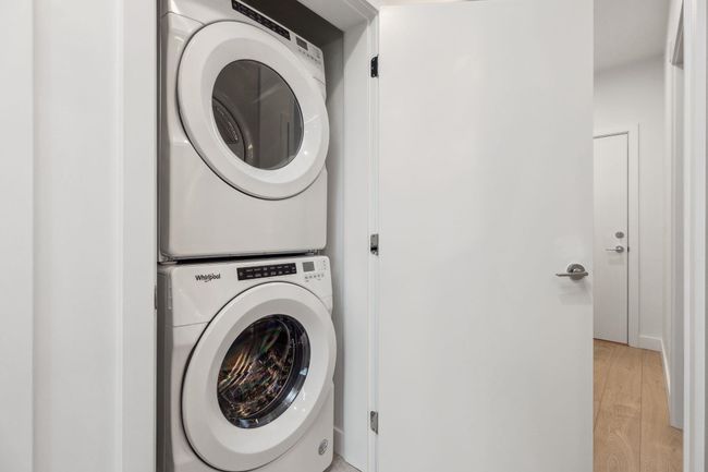 Laundry room with light wood-style flooring, stacked washer and clothes dryer, and laundry area | Image 14