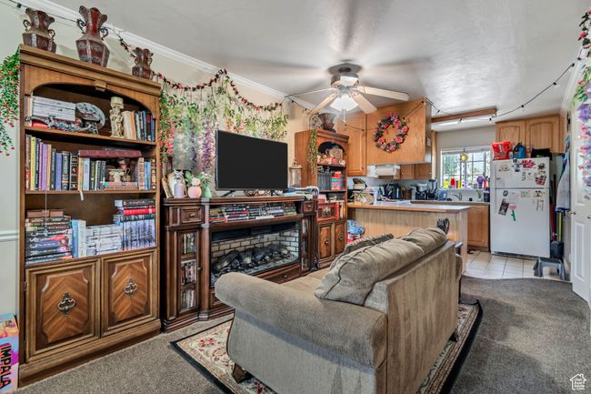 Living area featuring ceiling fan, light colored carpet, crown molding, and light tile patterned flooring | Image 4