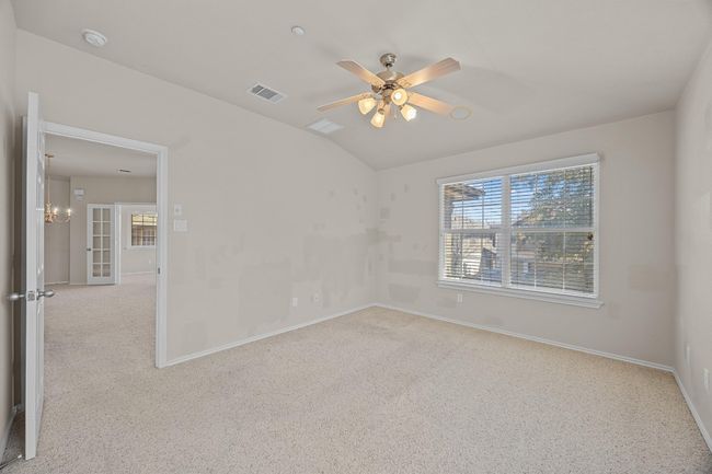 Carpeted empty room with a ceiling fan, visible vents, vaulted ceiling, and baseboards | Image 18