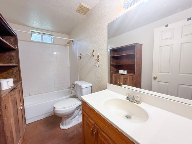 Bathroom with a textured ceiling, visible vents, a textured wall, toilet, and vanity | Image 6