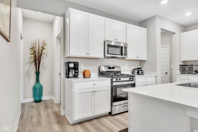 kitchen featuring white cabinetry, light wood-type flooring, light countertops, and appliances with stainless steel finishes | Image 12