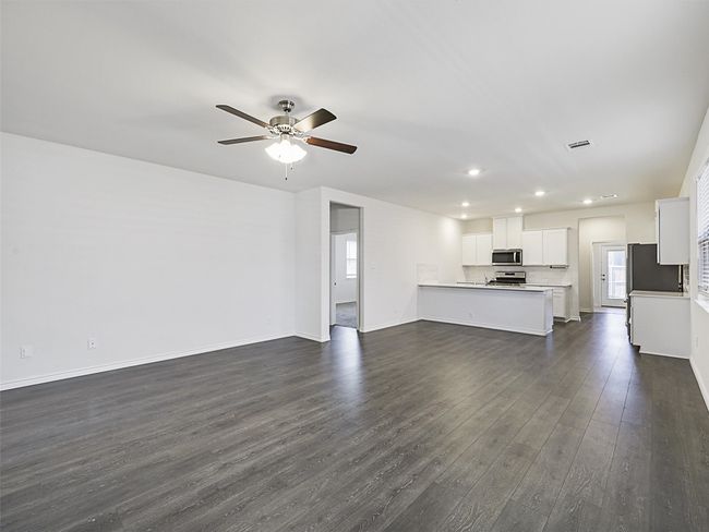 Unfurnished living room with dark wood-style floors, a ceiling fan, and recessed lighting | Image 5