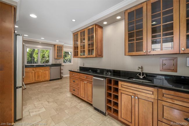 Kitchen featuring brown cabinetry, recessed lighting, crown molding, stainless steel appliances, and glass insert cabinets | Image 10