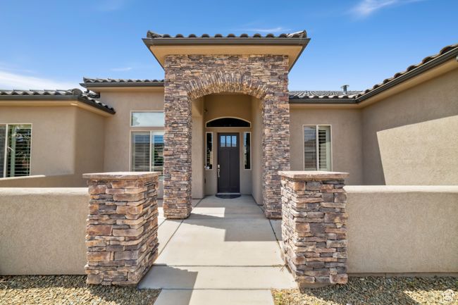 Doorway to property with stone siding, a tiled roof, and stucco siding | Image 6