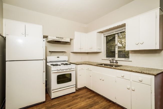 Kitchen featuring white appliances, under cabinet range hood, white cabinetry, and dark wood-style flooring | Image 13