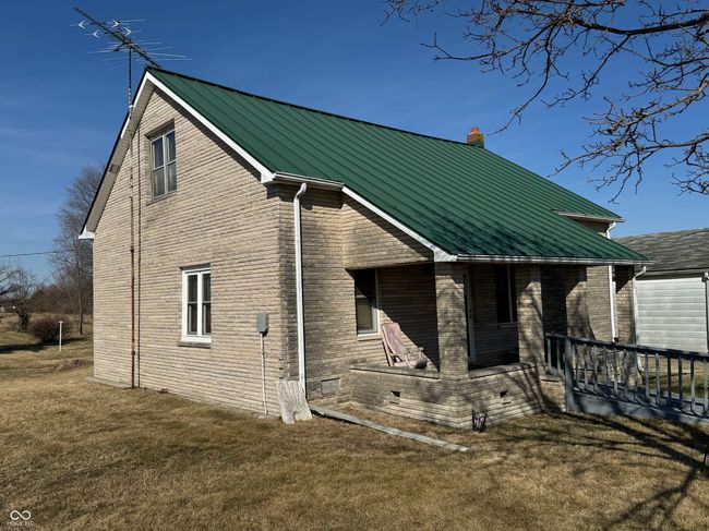 rear view of house featuring metal roof, a chimney, brick siding, a standing seam roof, and a lawn | Image 5
