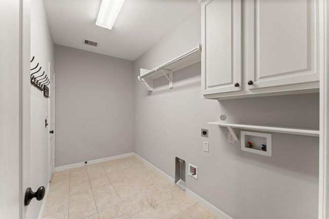 Expansive laundry room with upper cabinetry, hanging rod and ample storage. | Image 31