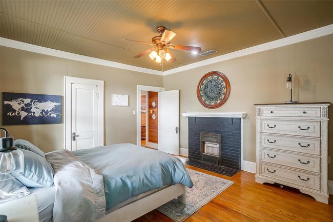 Bedroom with light wood-style flooring, ornamental molding, a brick fireplace, and a ceiling fan | Image 39