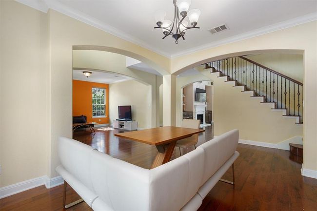 Living area featuring a fireplace, a chandelier, ornamental molding, baseboards, and hardwood / wood-style floors | Image 9