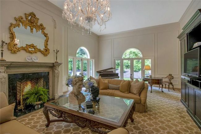 Living room with a notable chandelier, crown molding, and a high end fireplace | Image 9