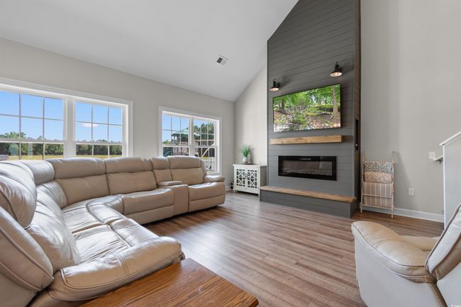 Living area with high vaulted ceiling, wood finished floors, and a large fireplace | Image 5