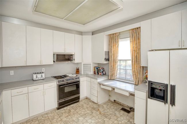 Kitchen featuring white cabinetry, light countertops, black range oven, and white fridge with ice dispenser | Image 14