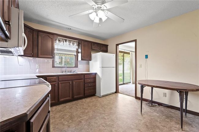 Kitchen featuring white appliances, a sink, dark brown cabinets, tasteful backsplash, and ceiling fan | Image 11