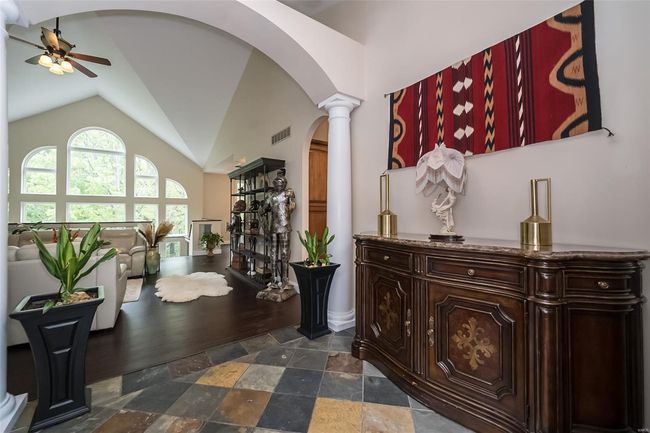 Corridor with visible vents, high vaulted ceiling, ornate columns, arched walkways, and stone finish flooring | Image 6