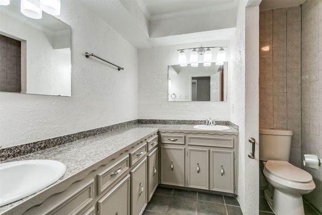 Bathroom featuring tile patterned flooring, a textured wall, toilet, vanity, and ornamental molding | Image 20