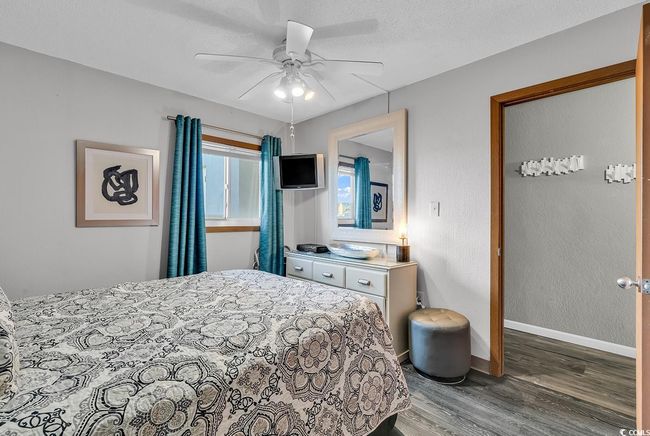 Bedroom with baseboards, a textured ceiling, wood finished floors, and a ceiling fan | Image 5