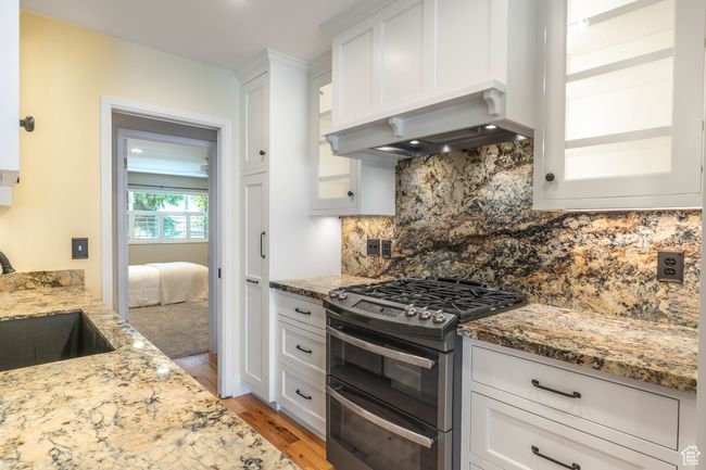 Kitchen featuring white cabinets, light stone counters, a sink, and double oven range | Image 11