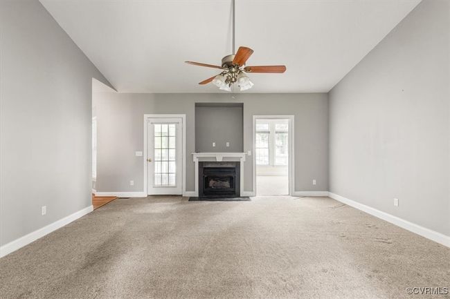 Unfurnished living room with ceiling fan, carpet flooring, a fireplace with flush hearth, and baseboards | Image 8