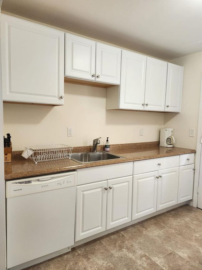 Kitchen featuring white dishwasher, white cabinets, and dark countertops | Image 5