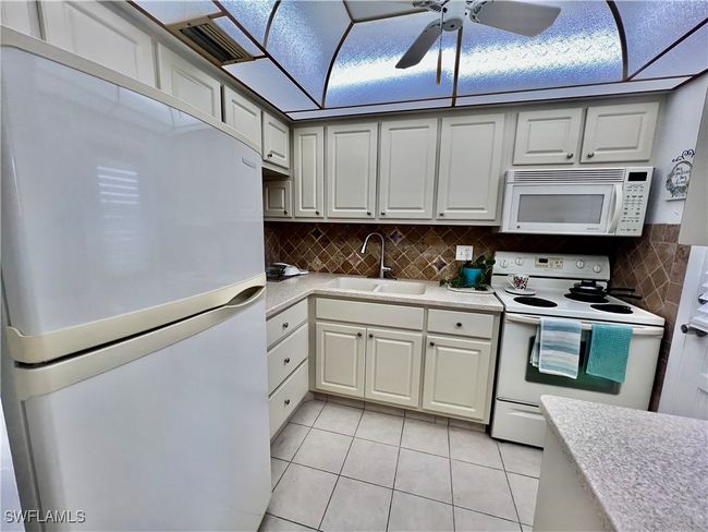 Kitchen with solid surface countertops and stone tile backsplash. | Image 4