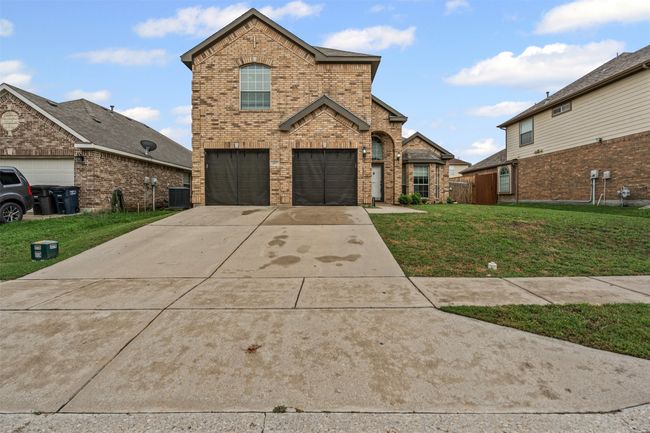 Traditional-style house featuring brick siding, an attached garage, and concrete driveway | Image 5