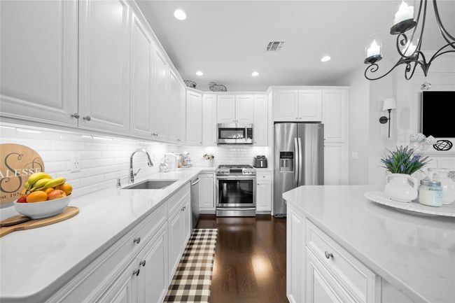 Kitchen with decorative backsplash, white cabinets, recessed lighting, appliances with stainless steel finishes, and a sink | Image 4