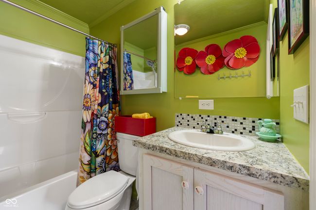 bathroom featuring crown molding, vanity, toilet, shower / bath combination with curtain, and decorative backsplash | Image 22
