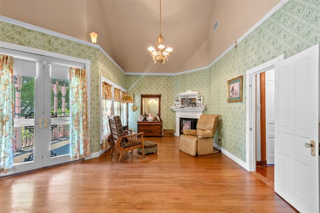 Living area featuring light wood finished floors, a fireplace, a notable chandelier, and wallpapered walls | Image 26