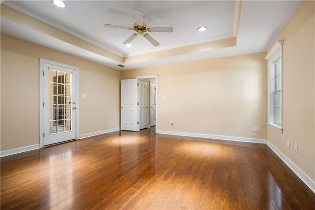 Unfurnished room featuring a tray ceiling, ceiling fan, ornamental molding, hardwood / wood-style floors, and recessed lighting | Image 17
