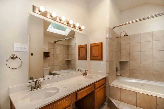 Full bathroom featuring tiled shower / bath, double vanity, and a skylight | Image 13