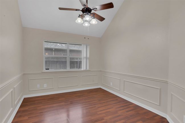 Empty room featuring ceiling fan, vaulted ceiling, dark wood-style floors, a wainscoted wall, and a decorative wall | Image 19