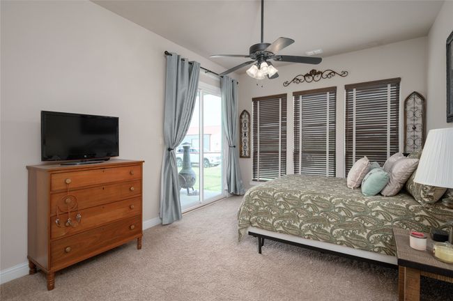 Bedroom with light colored carpet, baseboards, a ceiling fan, and access to back porch. | Image 21