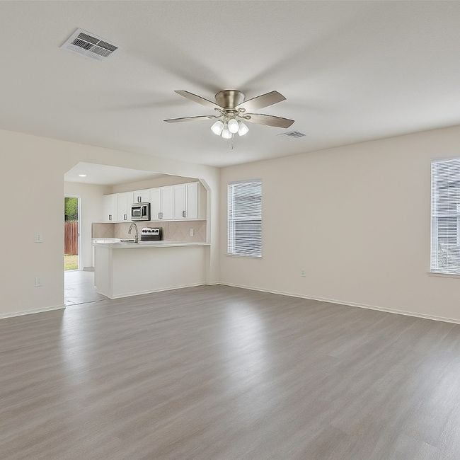 Unfurnished living room with light wood-type flooring, a ceiling fan, baseboards, and a sink | Image 8