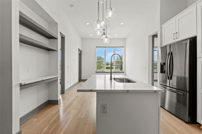 Kitchen featuring stainless steel fridge with ice dispenser, a sink, light stone countertops, light wood-style flooring, and recessed lighting | Image 7