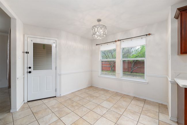 featuring light tile patterned floors, a notable chandelier, and baseboards | Image 8
