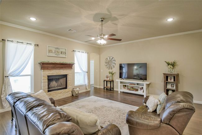 Living area with baseboards, wood finished floors, and a fireplace | Image 7