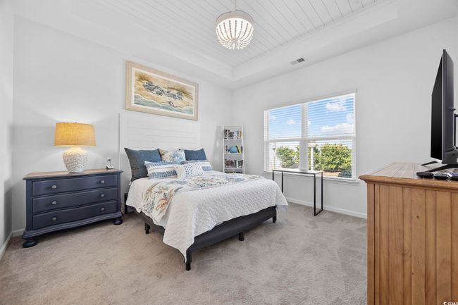 Bedroom featuring visible vents, baseboards, light carpet, a tray ceiling, and wooden ceiling | Image 21