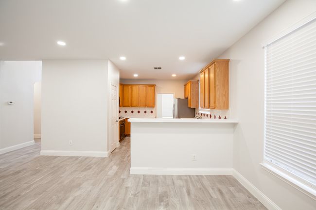 Kitchen featuring freestanding refrigerator, light wood-type flooring, light countertops, a peninsula, and recessed lighting | Image 15