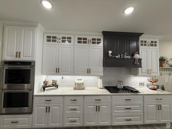 Kitchen with glass insert cabinets, white cabinetry, stainless steel appliances, and backsplash | Image 23